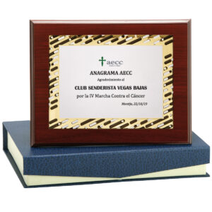 Placa homenaje metálica perfil dorado-negro colocado sobre madera